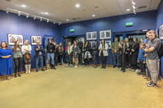 Sala z wystawionymi zdjęciami i liczna grupa ludzi stojących blisko ściany, fot. B.Motyka 