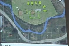 Na zdjęciu widoczny jeden z wyświetlanych slajdów. Na mapie zaznaczone lokalizacje mniejszych obiektów i ciek wodny. Pod mapą na białym tle wyjaśnienie oznaczeń graficznych.