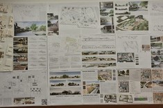 Na ścianie wywieszone plansze na białym tle umieszczone kolorowe grafiki wraz z opisami. Po lewej stronie dwie makiety w jasnej kolorystyce przedstawiające projekt targowiska.