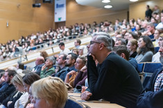 Zbliżenie na słuchaczy wykładu siedzących w rzędach.