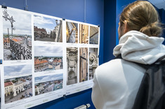 Na ciemnogranatowej ścianie zawieszona jest plansza z kilkoma kolorowymi fotografiami.