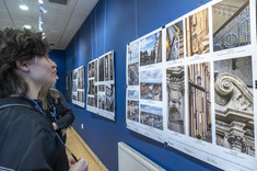 Na ciemnogranatowej ścianie zawieszone są trzy plansze, na każdej po kilka kolorowych fotografii.