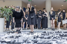 Dwie kobiety, prowadzące przedmiot, przyglądają się kompozycji modeli ułożonych na podłodze.