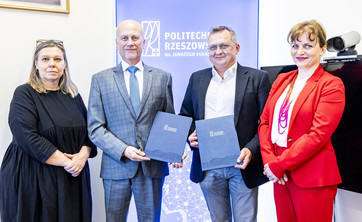 Na zdjęciu stoją obok siebie cztery osoby, dwóch mężczyzn i dwie kobiety po lewej i prawej stronie. Mężczyźni trzymają w ręku dokumenty.  W tle na niebieskiej planszy biały napis Politechnika Rzeszowska.