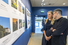 Kobieta i mężczyzna ubrani na czarno stoją obok siebie i przyglądają się wystawie.