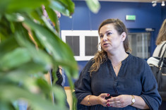 Na pierwszym planie kobieta z długimi włosami ubrana na czarno.