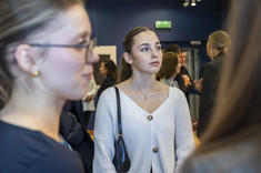 Zdjęcie grupy osób na tle wystawy. Na pierwszym planie dwie młode kobiety.