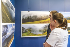 Dwie kobiety przyglądają się planszom z fotografiami pejzaży górskich.