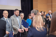 Na zdjęciu kilkanaście oficjalnie ubranych osób podczas wręczania nagród.