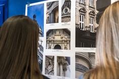 Na ciemnogranatowej ścianie zawieszona jest plansza z kilkoma kolorowymi fotografiami.